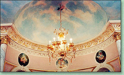 La coupole h&eacute;misph&egrave;rique qui surplombe
la rotonde est peinte d'un ciel nuageux o&ugrave; 
un angelot "porte" le lustre principal